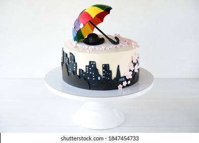 
Birthday cake decorated with city silhouette, colorful umbrella, hat and flowers