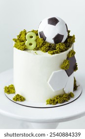 Birthday cake for a football fan boy or player decorated with soccer ball and green edible grass. White background