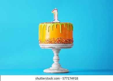 Birthday cake with one candle on blue background