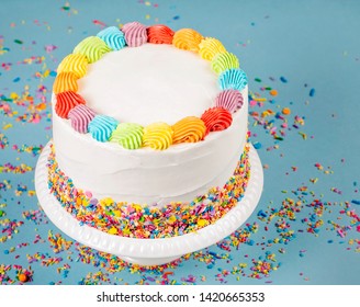 Birthday Cake With Rainbow Icing And Colorful Sprinkles Over A Blue Background.