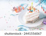 Birthday cake slice on birthday party decorated table.  Slice of Birthday Cake with white whipped cream, sugar sprinkles funfetti and candle, copy space