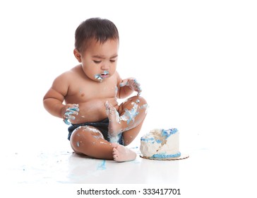 Birthday cake smash.  Adorable baby boy eating a small birthday cake.  Isolated on white.