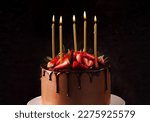 Birthday chocolate cake with candles. Candles on top of a birthday cake with strawberry black background