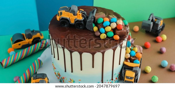Birthday\
colorful cake for little boy with toy cars and colorful candies\
decorations. Holiday, celebration, stylish concept. Construction\
and transportation theme boys party.\
Banner.