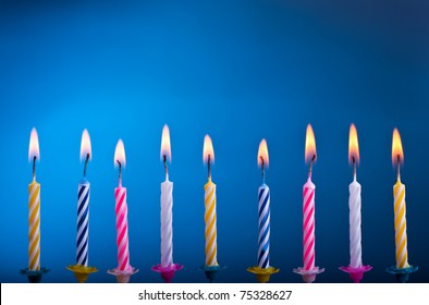 Birthday colour candles with fire on blue background