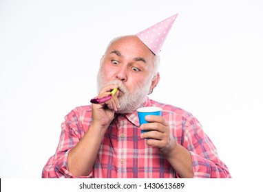 Birthday concept. Ideas for seniors birthday celebrations. Man bearded grandpa with birthday cap and drink cup. Grandfather graybeard blowing party whistle. Getting older is still fun. Elderly people.