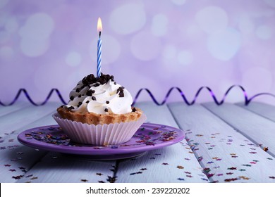 Birthday Cup Cake With Candle On Plate On Color Wooden Table And Light Background