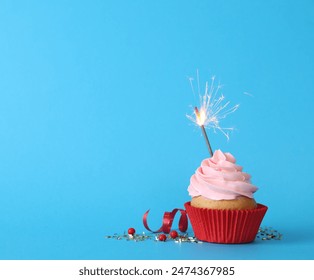 Birthday cupcake with burning sparkler on light blue background. Space for text - Powered by Shutterstock