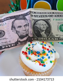 Birthday cupcake with gift money. White cake with white frosting and rainbow sprinkles. Colorful party hats. President's day concept. Portraits of the presidents.