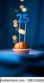 Birthday cupcake or muffin with number twenty five (25) and lights on the blue background. Birthday or anniversary concept
