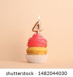 Birthday cupcake with number four candle on beige background