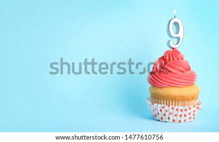 Birthday cupcake with number nine candle on blue background, space for text