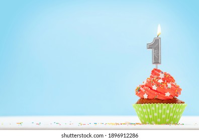 Birthday cupcake with number one burning candle over blue background with copy space for your greetings