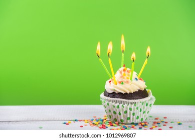 Birthday cupcake on a color background with multicolor candles.
