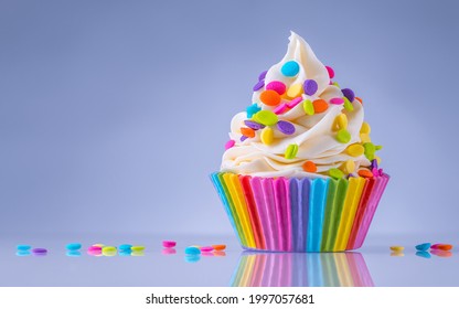 Birthday Cupcake. Rainbow Paper Cup Liners. Happy Birthday. Celebration Holidays. LGBT Pride. Tasty Baking Cupcakes, Cake Or Muffin With White Cream Icing, Frosting, Bright Colored Sprinkles Or Candy.