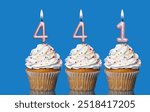 Birthday Cupcakes With Candles Lit Forming The Number 441 - Photo On Blue Background