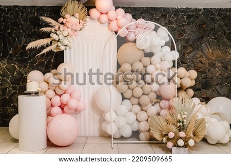 Birthday decorations - balloons, garland and decor for little baby party on a wall background. Celebration baptism concept. Baby text. Trendy Cake.