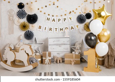 Birthday decorations with gifts, toys, balloons, garland and figure 1 for little baby party on a white wall background.