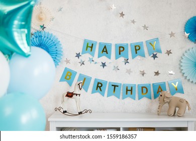 Birthday decorations with gifts, toys, balloons, garland and figure 3 for little baby party on a white wall background.