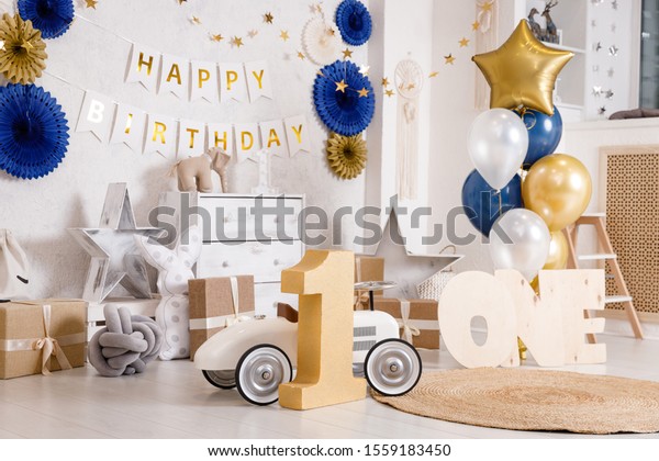 Birthday\
decorations with gifts, toys, balloons, garland and figure 1 for\
little baby party on a white wall\
background.