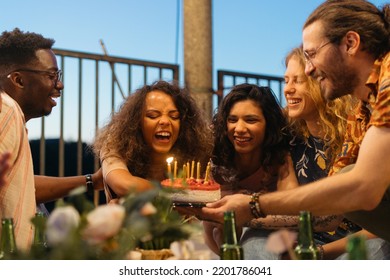 A Birthday Girl Celebrates Her Birthday At The Summer Rooftop Party. Her Friends Hold A Cake With One Unblown Candle And Laugh.