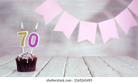 Birthday number 70. Festive background for a girl or woman with a muffin and candles burning pink in pastel colors with decorations for any holiday, copy space, women's gift boxes, place for text. - Shutterstock ID 2163161493