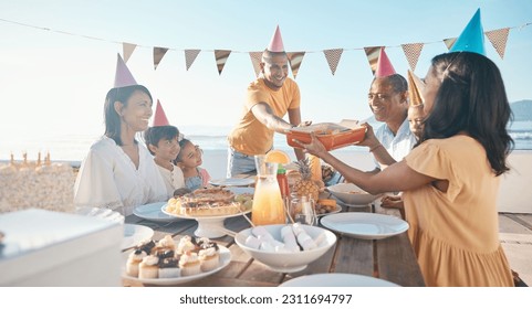 Birthday, parents and children with food by beach for event, celebration and party outdoors. Family, social gathering and mother, father with kids at picnic with cake, presents and eating together - Powered by Shutterstock