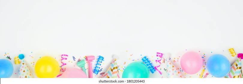 Birthday Party Banner With Bottom Border On A White Background. Top Down View With Balloons, Party Hats, Streamers And Confetti. Copy Space.