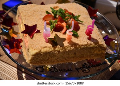 Birthday party cake decorated with fresh red strawberries, three colorful spiral shaped candles, shiny tinsel stars and chocolate inscription "Happy  birthday" in Cyrillic letters of Russian language - Powered by Shutterstock