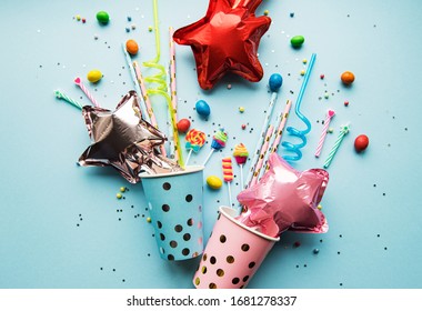 Birthday party caps,  paper straws, candy and baloons on blue background