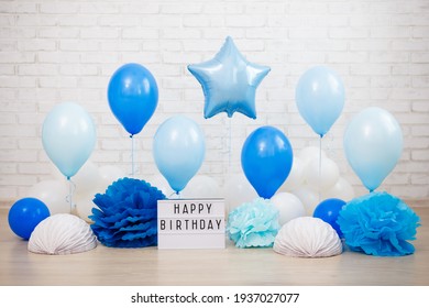 Birthday Party Decoration - Air Balloons, Paper Balls And Lightbox With Happy Birtday Text Over White Brick Wall