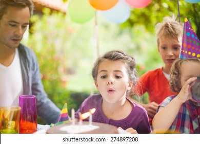 Birthday party in family. Girl blowing candles with her siblings