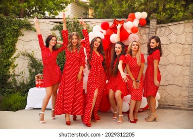 Birthday party. Group of female friends enjoying and laughing. Women in dresses having fun by Photo zone from red and white balloons. Ladies day, concept of friendship. 