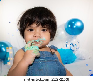 Birthday Photo Session Of A Hispanic Baby With Overalls Eating Cake