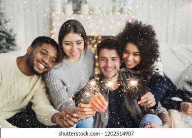 Birthday or winter holidays celebration, greeting card mockup. Happy multiethnic friends holding bengal lights, copy space