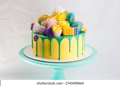 Birthday yellow cake with green melted chocolate, cake pops, cupcake, chocolate bar and donut. Copy space.
