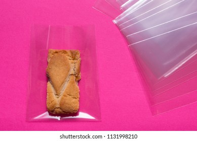 Biscuit In Cellophane Bag On Pink Background