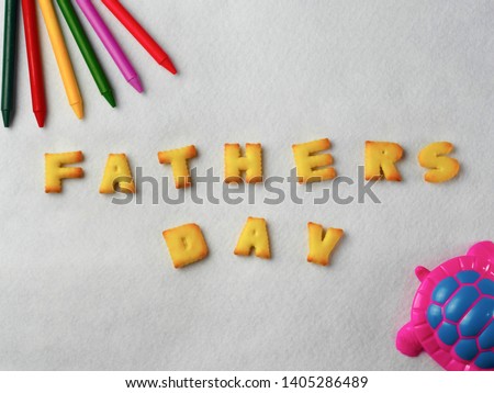 Biscuits, letters, shapes and colorful crayons,plastic toys arranged on a white background for Father's Day