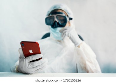 Bishkek, Kyrgyzstan - Marth 14 2020: Bio Hazard Man With Iphone. Doctor Looking For Situation In World, In Protective Suit.