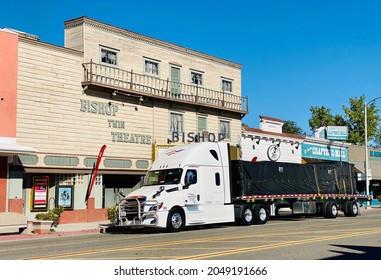 Bishop, CA - September 19, 2021: Semi Flatbed Truck Driving Next To A Historic Theatre Building In Old Town.