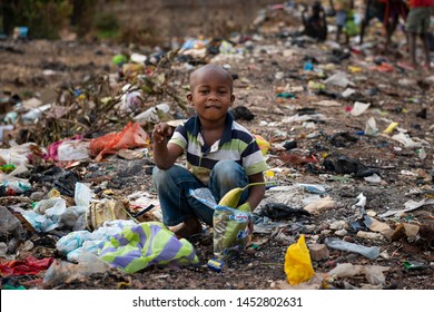 Bissau, Republic Of Guinea-Bissau - February 8, 2018: Young African Boy Picking Up Garbage At A Landfill In The City Of Bissau, In Guinea-Bissau, West Africa