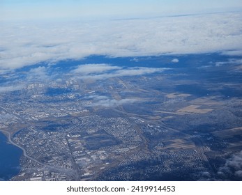 A bit of  cloud cover hovering over a large populated area that is seen stretching out for miles from above.