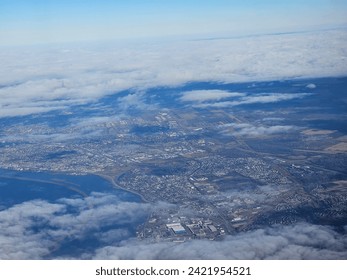 A bit of  cloud cover hovering over a large populated area that is seen stretching out for miles from above.