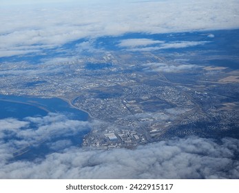 A bit of  cloud cover hovering over a large populated area that is seen stretching out for miles from above.