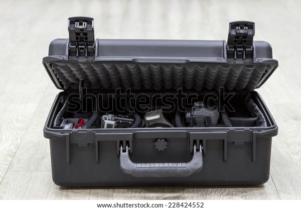 Bit open plastic case on floor with photo\
equipments in dividers