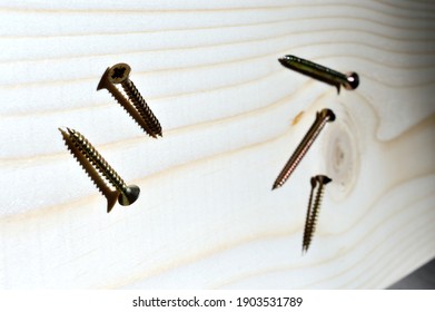 a bit for a screwdriver and a few self-tapping screws lie on a piece of wood. close-up.