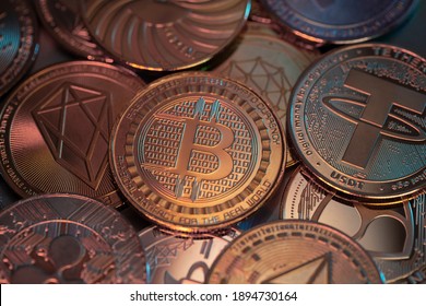 Bitcoin BTC and altcoins cryptocurrency physical coins placed on top of each other and lit with red and blue lights.