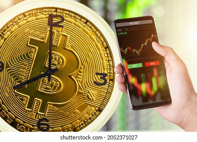The Bitcoin Clock represents the time of trading cryptocurrency. and trader investor analyst using mobile phone app analytics for cryptocurrency financial