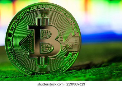 Bitcoin coin in green neon light close-up. World cryptocurrency. The financial system of the future
