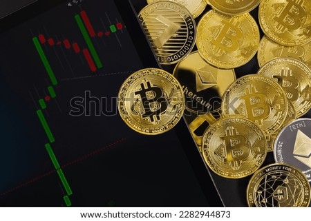 Bitcoin coin on digital tablet with graph by various coins